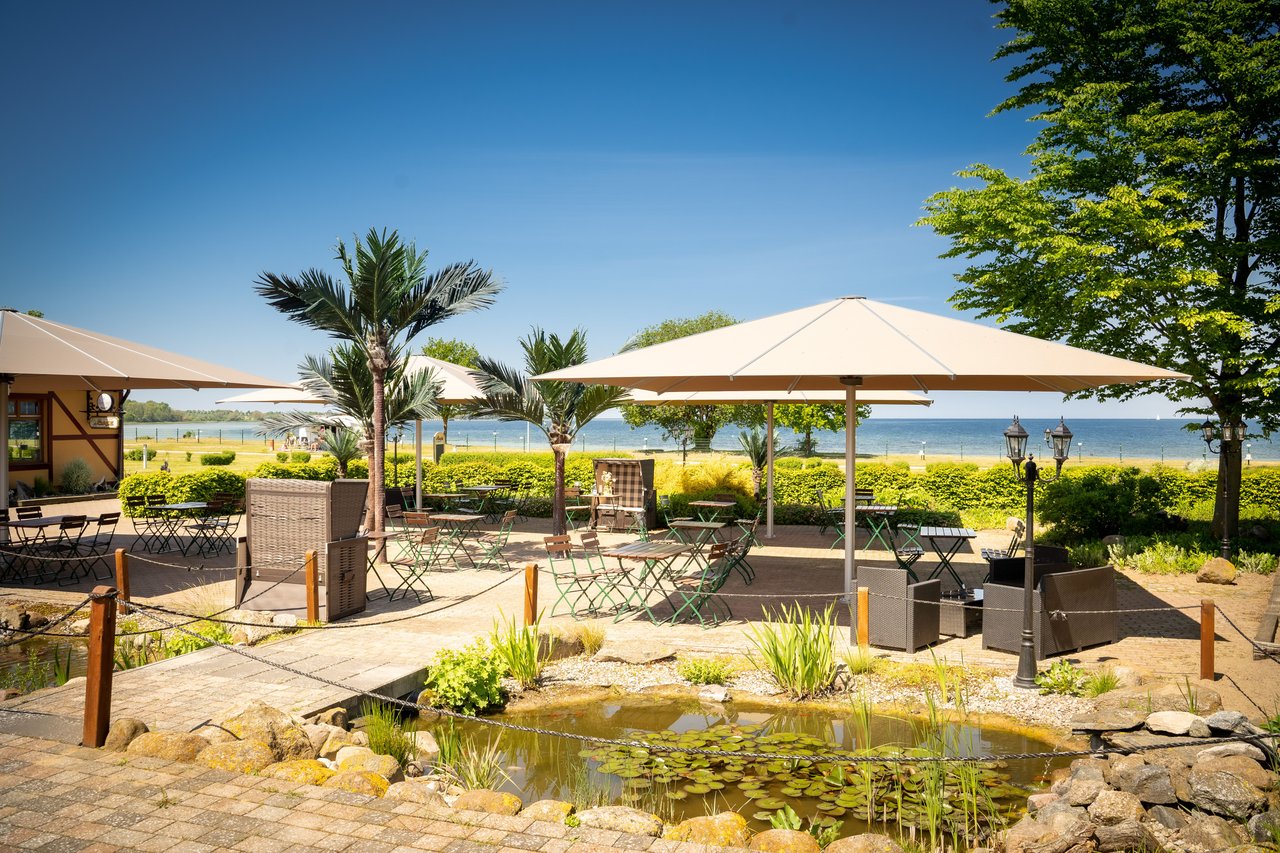 Sonnenschirme über Sitzplätzen in einem Camping-Resort am Wasser