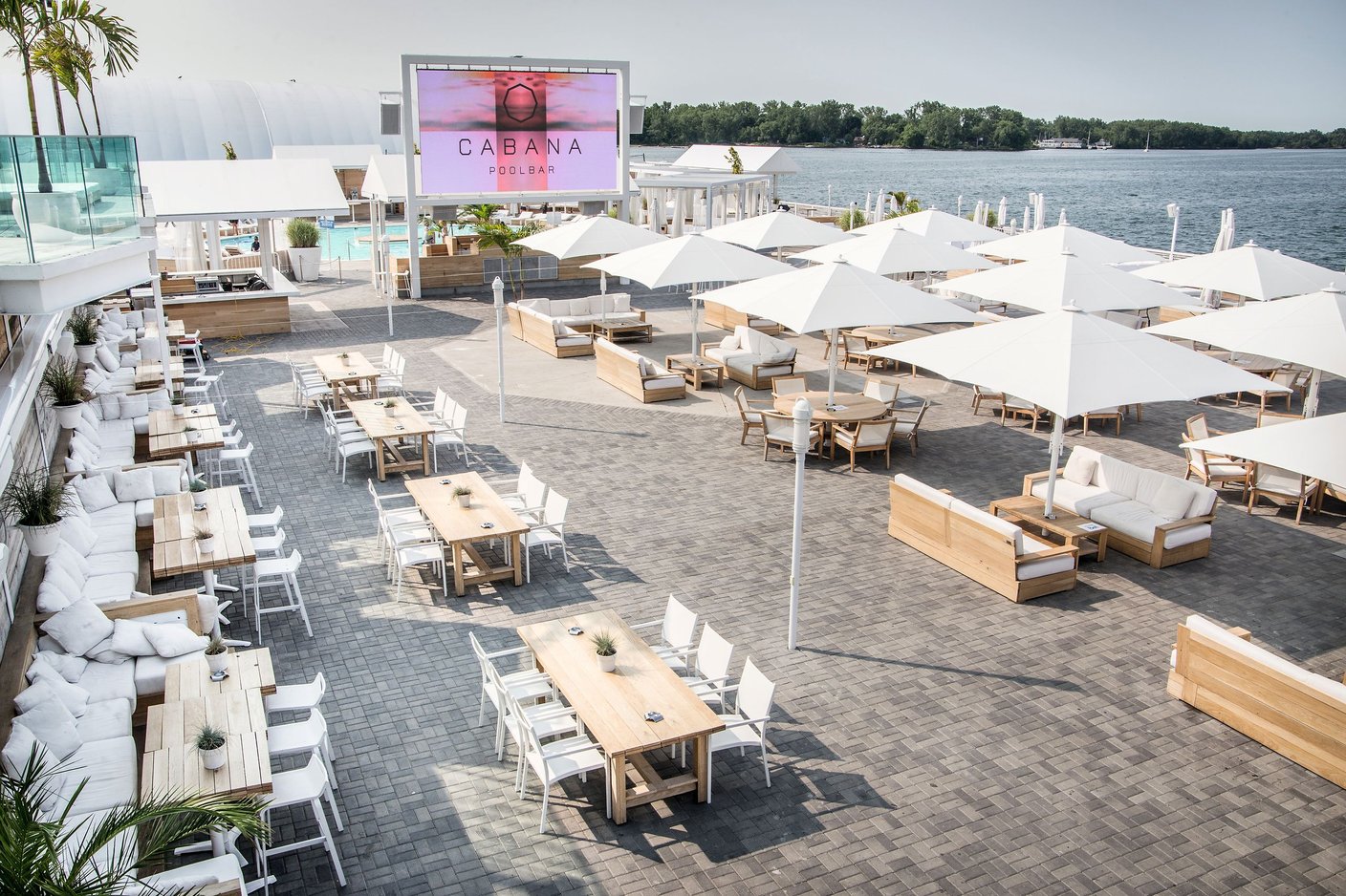 Rooftop-Terrasse mit vielen eingedeckten Tischen unter weißen Bahama Großschirmen