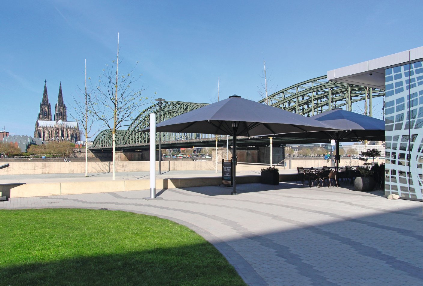 Bahama Großschirm auf einer Terrasse am Rhein mit Kölner Dom und Hohenzollernbrücke im Hintergrund
