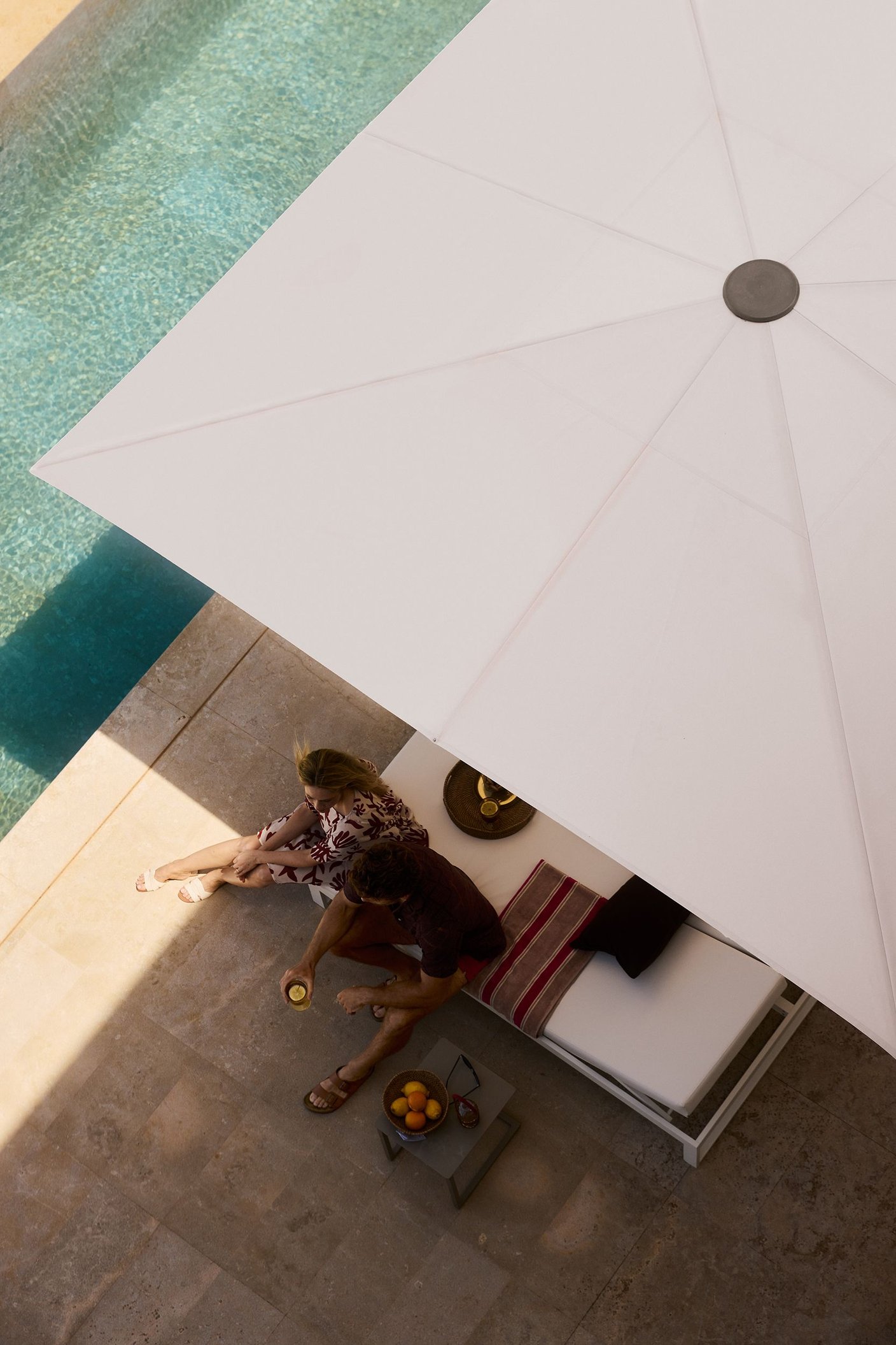 Blick von oben auf einen geöffneten Glatz Fortello, der eine Poollounge mit zwei Personen beschattet