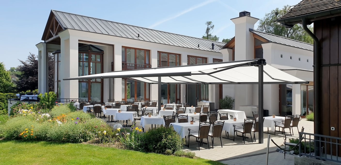 Frei stehende markilux syncra Markisenanlage über einer weiß eingedeckten Restaurantterrasse