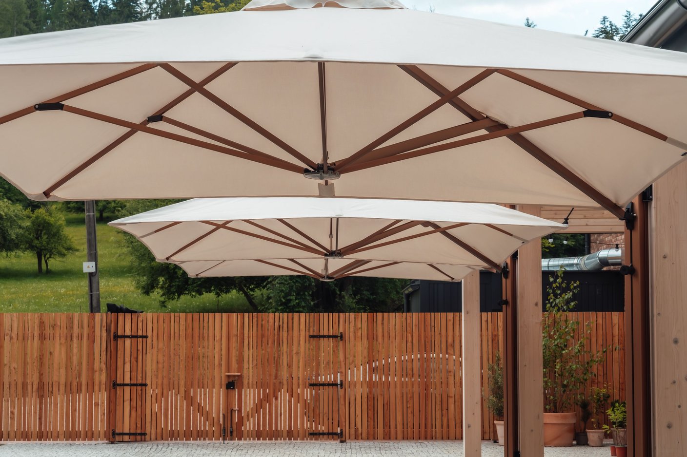 Zwei Prostor P6 in Sandweiß aus der Nähe, sichtbare Streben und Kupfermast über einer Gartenterrasse