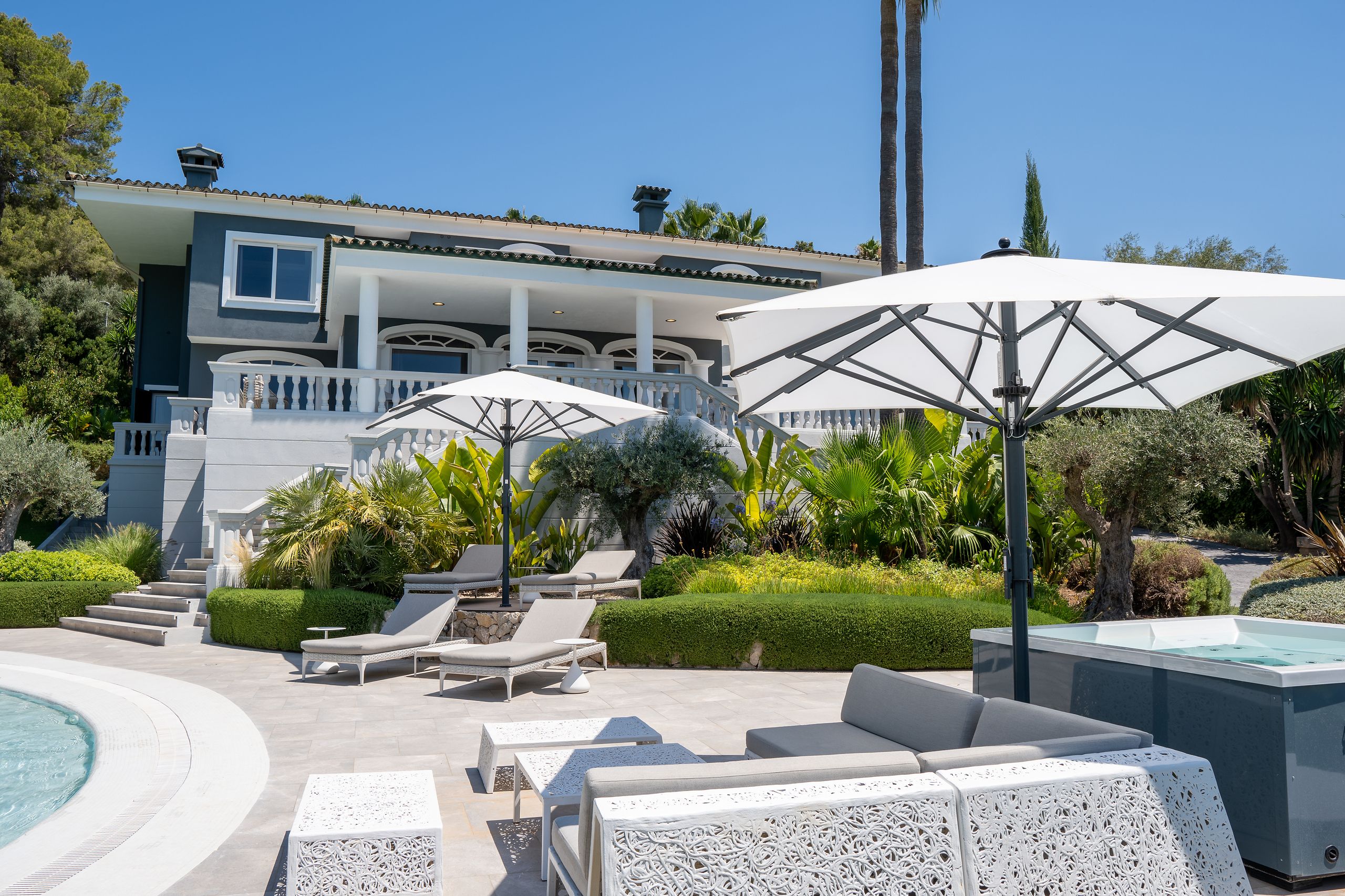 Weißer Bahama Jumbrella Großschirm an der Poolterrasse eines modernen Wohnhauses