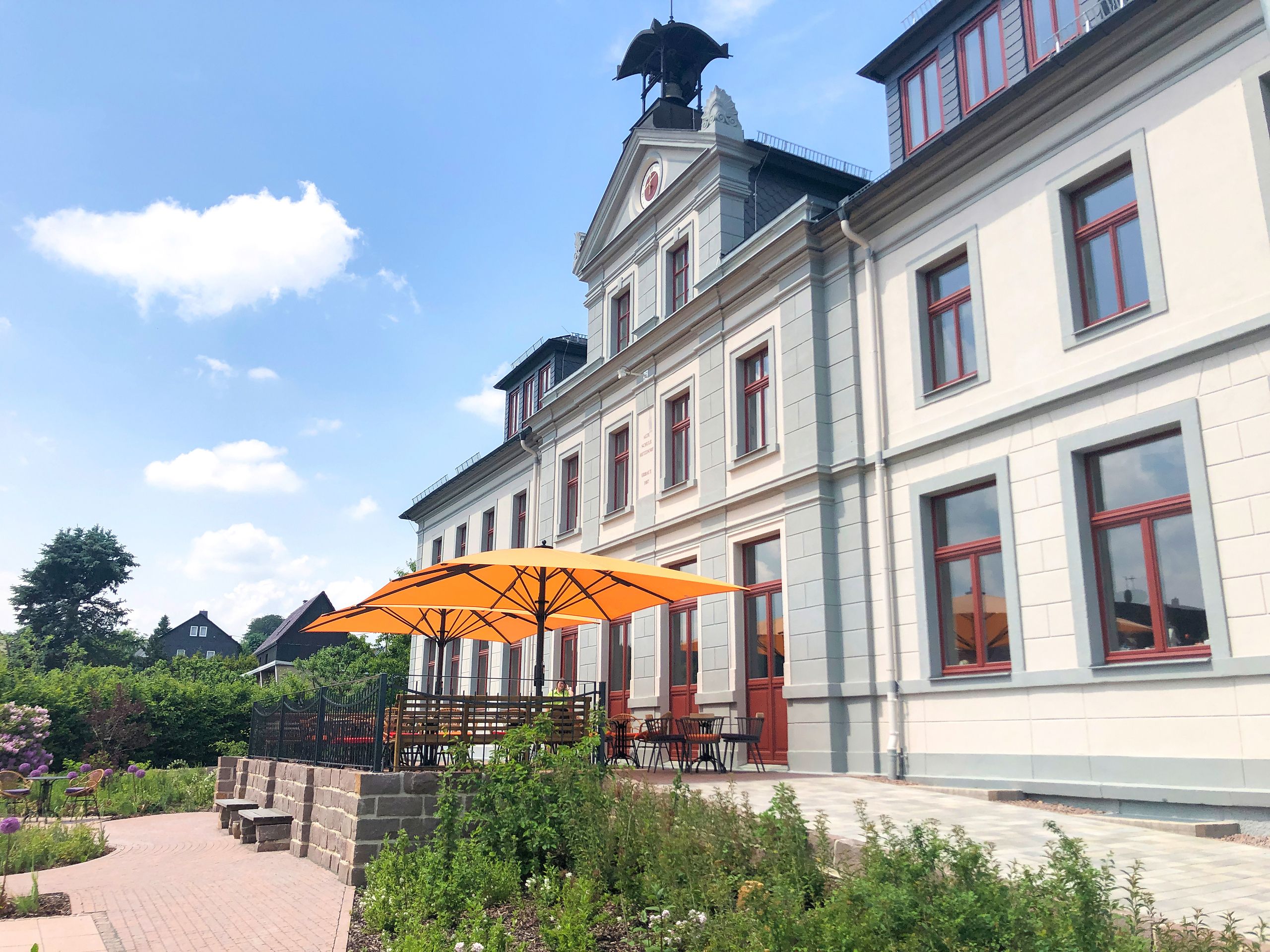 Orange und weiße Bahama Jumbrella Großschirme vor dem Café Alte Schule in Hetzdorf