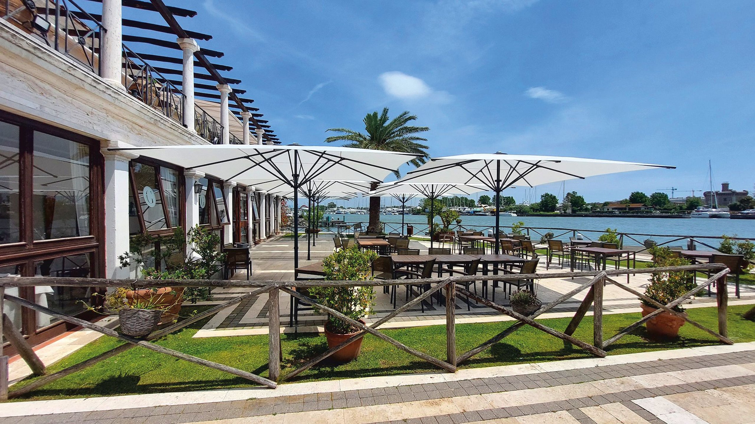 Weiße Bahama Pure Gartenschirme über einer Restaurantterrasse am Yachthafen