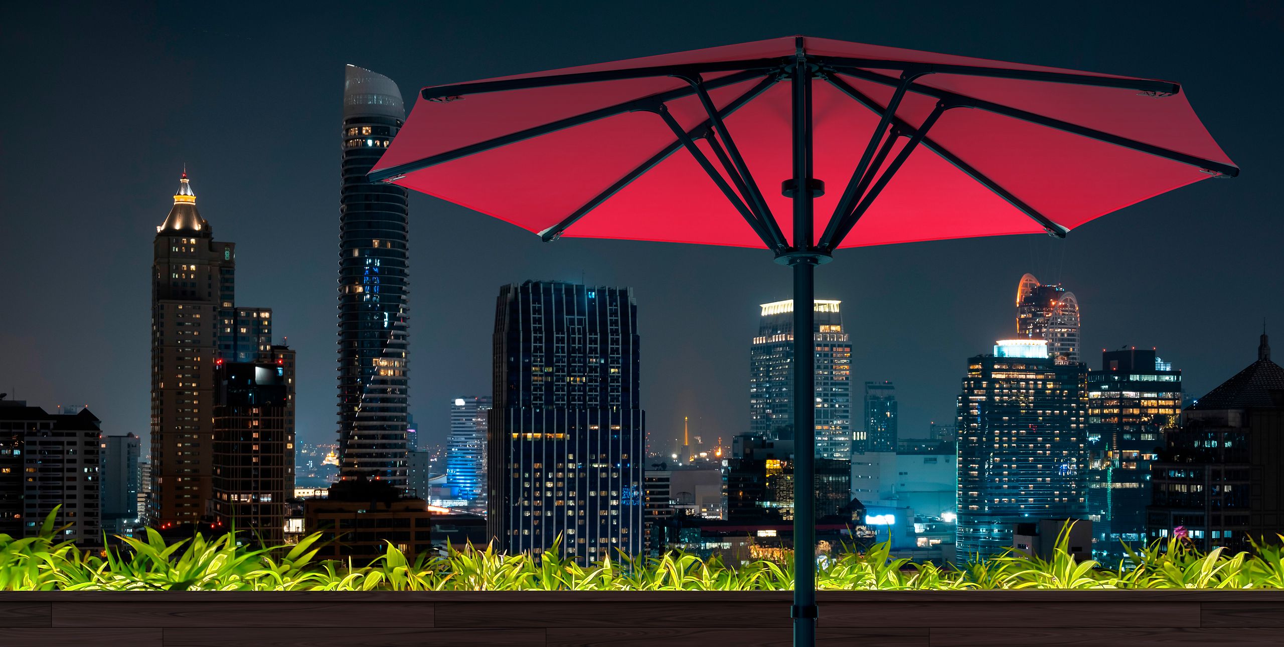 Roter runder Bahama Pure auf einer Dachterrasse vor nächtlicher Skyline