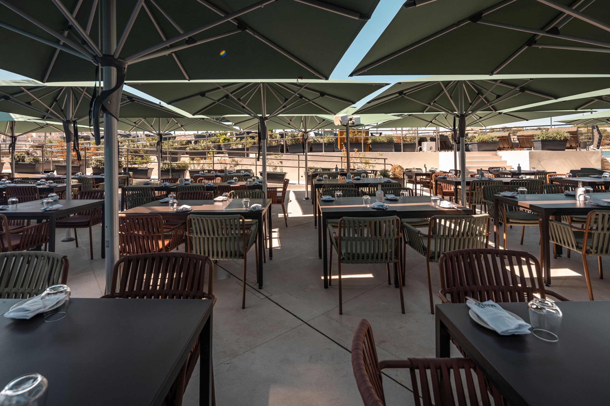 Grüne Glatz Fortello über den gedeckten Tischen einer Restaurant-Terrasse am Meer