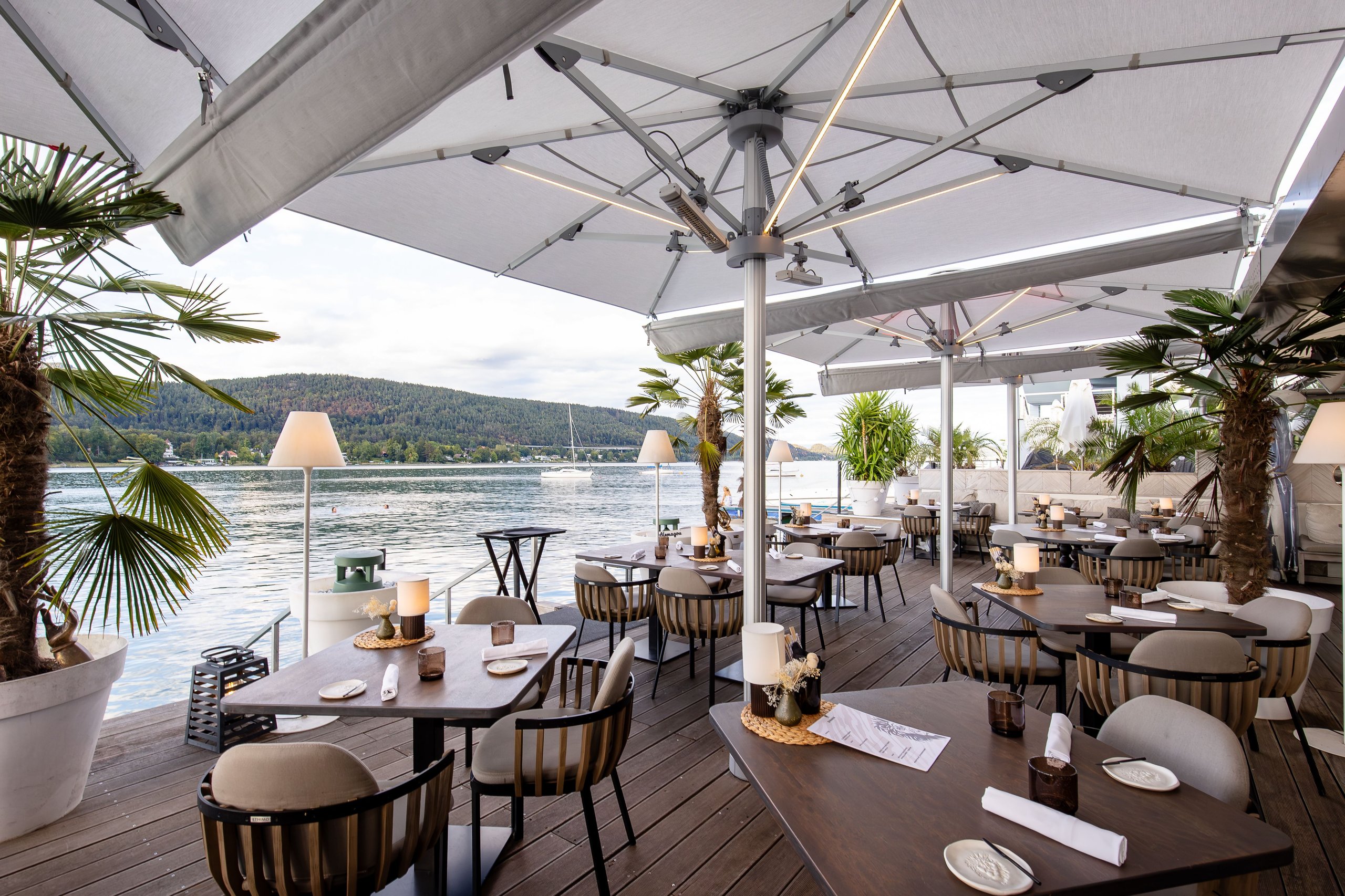 Weiße Palazzo-Noblesse-Schirme mit LED-Unterseite über der Seeterrasse des SOL Beach Club am Wörthersee