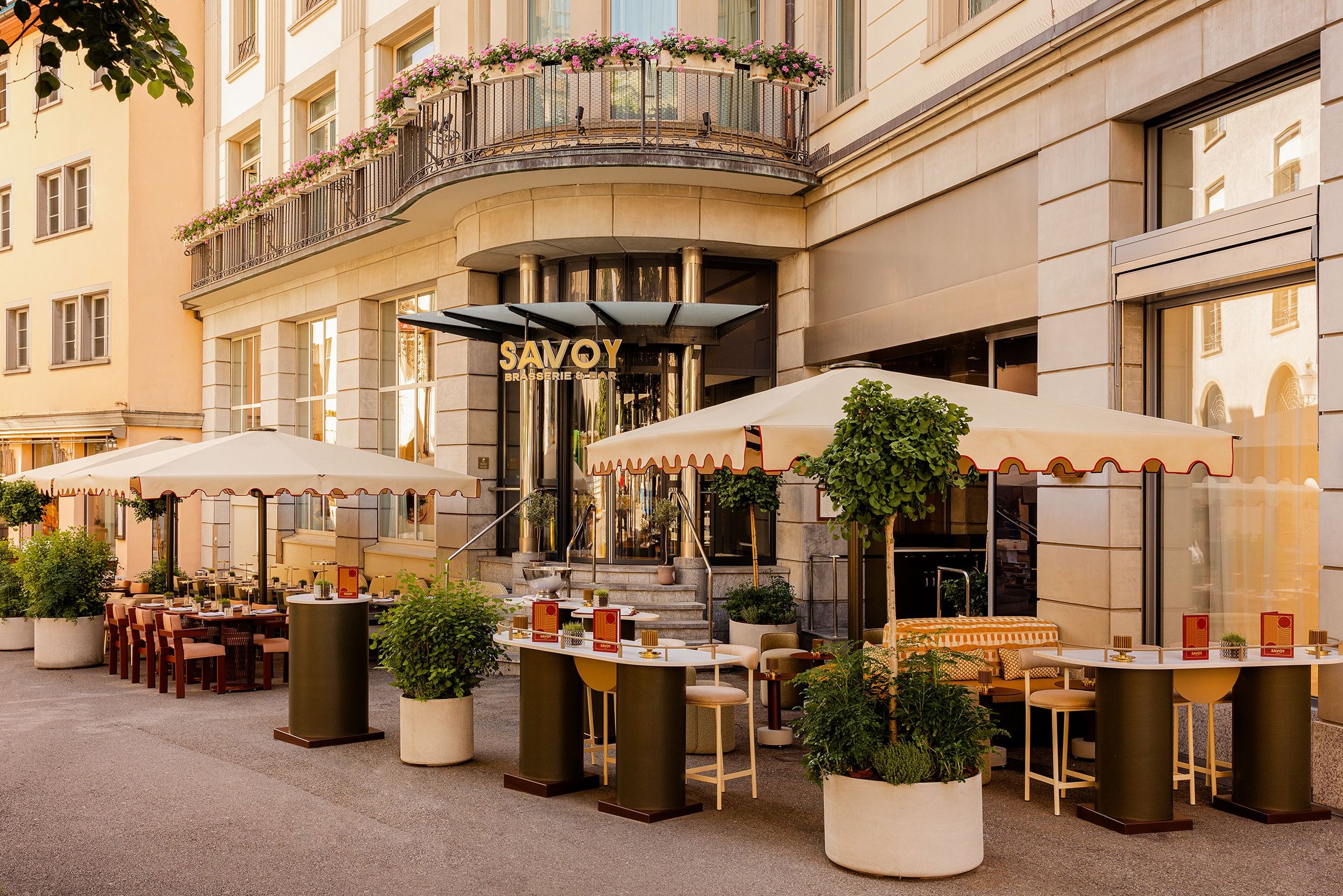 Cremefarbene Glatz Palazzo-Noblesse-Großschirme mit rotem Volant vor dem Hotel Savoy in Zürich, Terrasse am Abend
