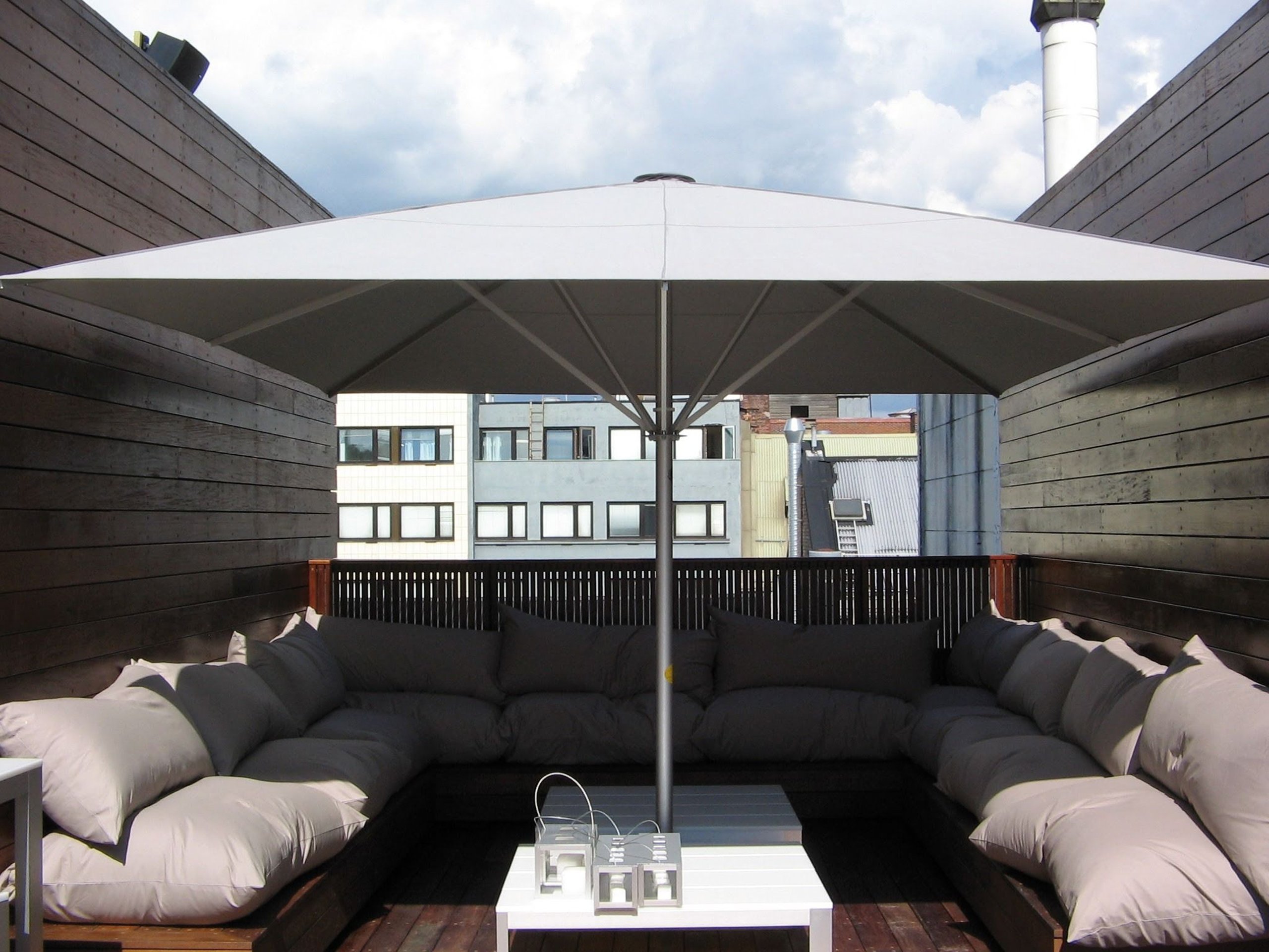 Weißer SCHATTELLO über einer Lounge mit grauen Polstern auf dunklem Holzdeck, Dachterrasse des Grims Grenka in Oslo