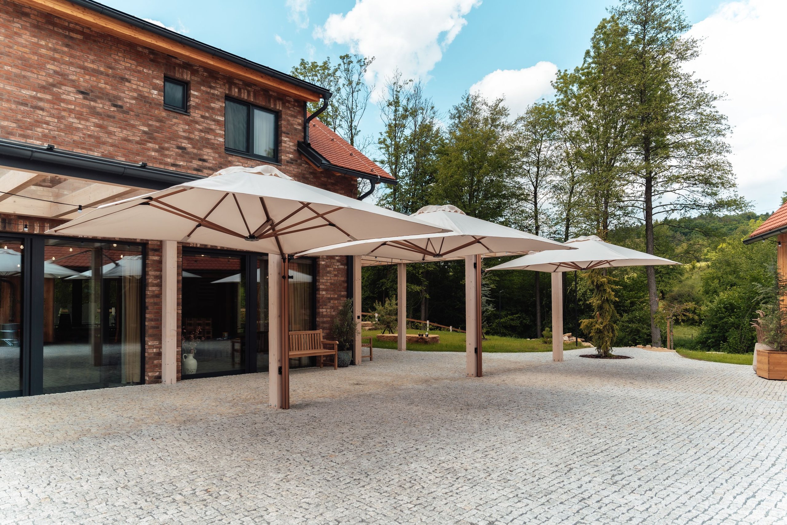 Mehrere Prostor P6 in Sandweiß auf Kupfermasten über einer Gartenterrasse am Backsteinhaus