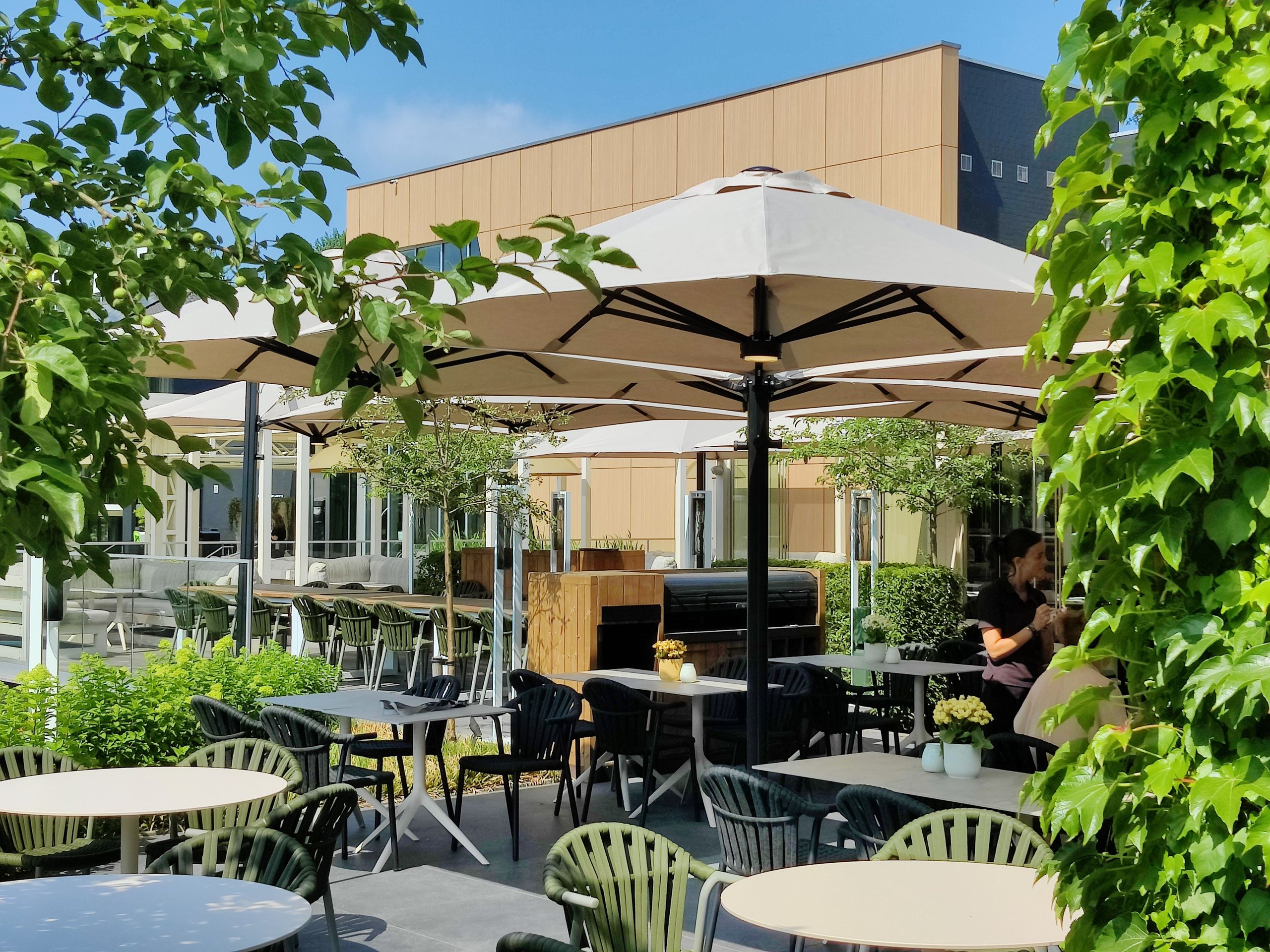Prostor P6 in Sandweiß über den Tischen einer begrünten Restaurantterrasse