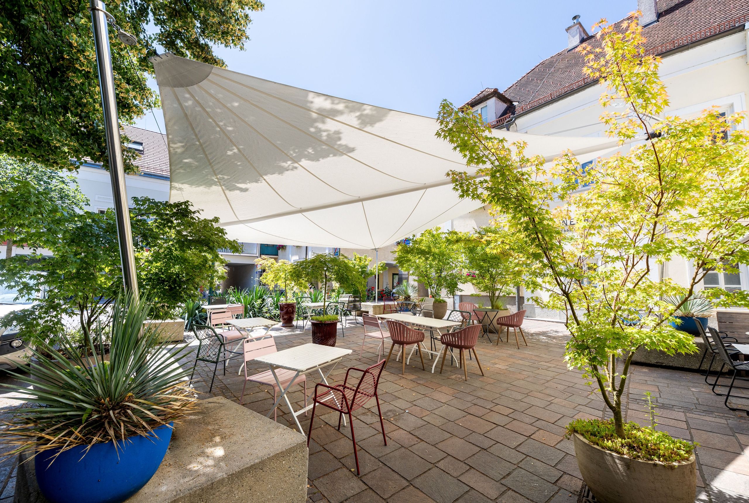 SunSquare Sonnensegel über einer Innenhof-Terrasse mit Ahornbäumen