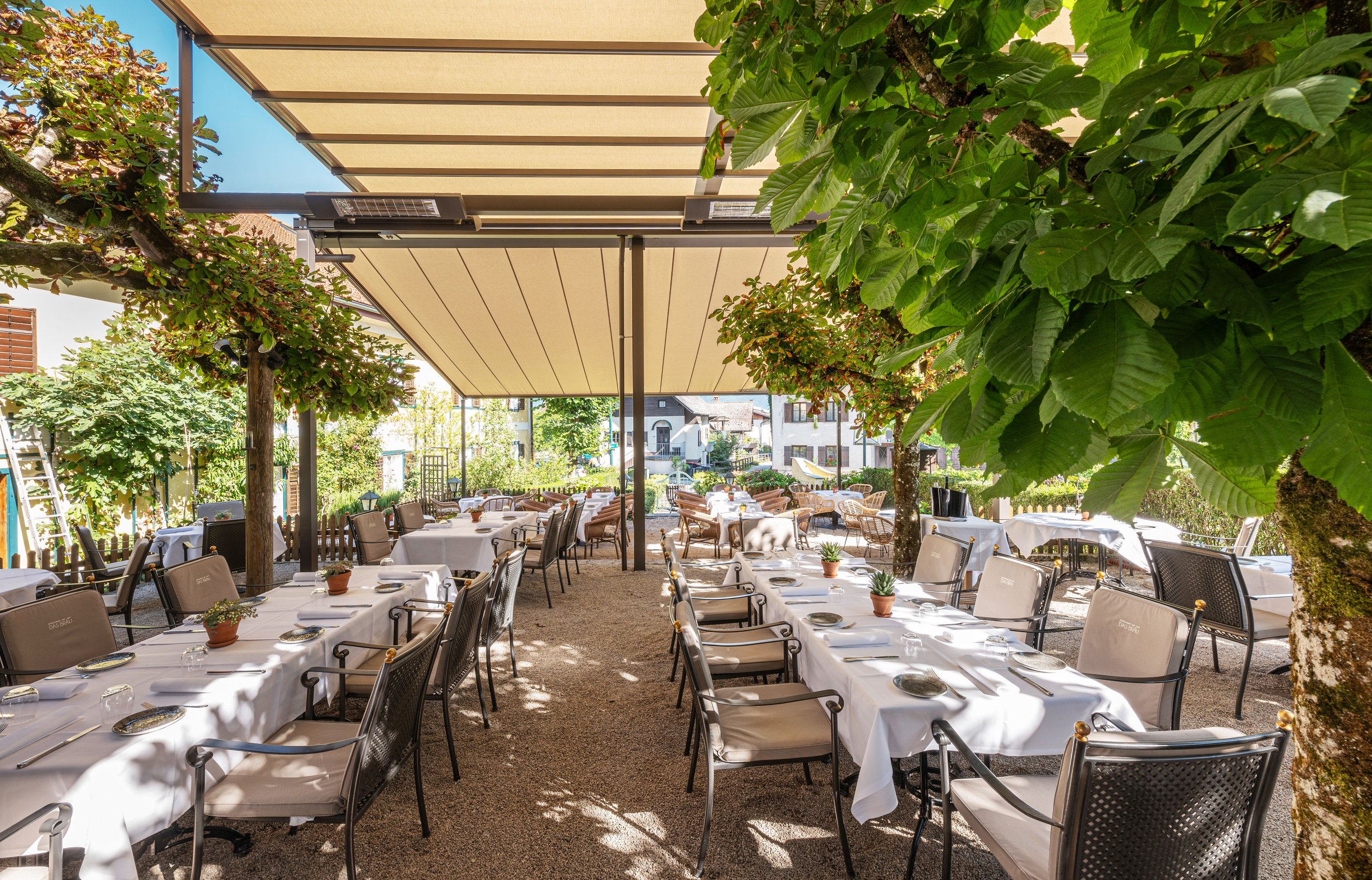 markilux Pergolamarkise über einem Gastgarten mit weiß eingedeckten Tischen