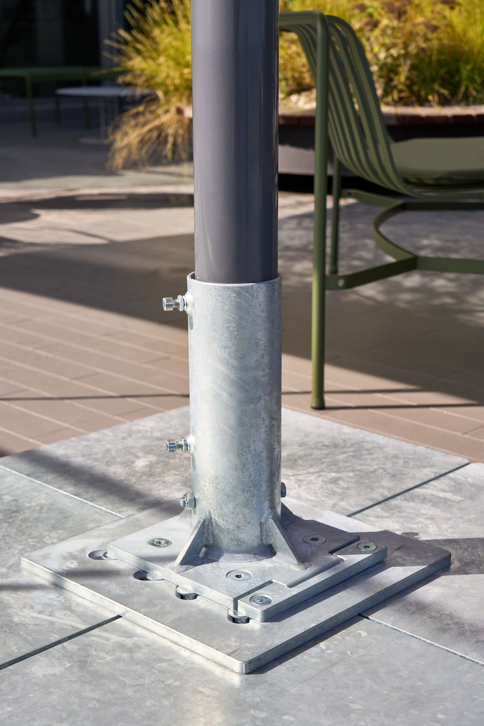 Verschraubter Mastfuß eines Großschirms auf einer Terrasse