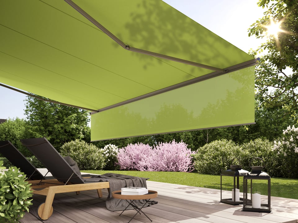 Blick von der Terrasse auf das herabgefahrene Schattenplus-Tuch der markilux 1600 – Sonnenliege im Vordergrund, Kirschblüten im Hintergrund