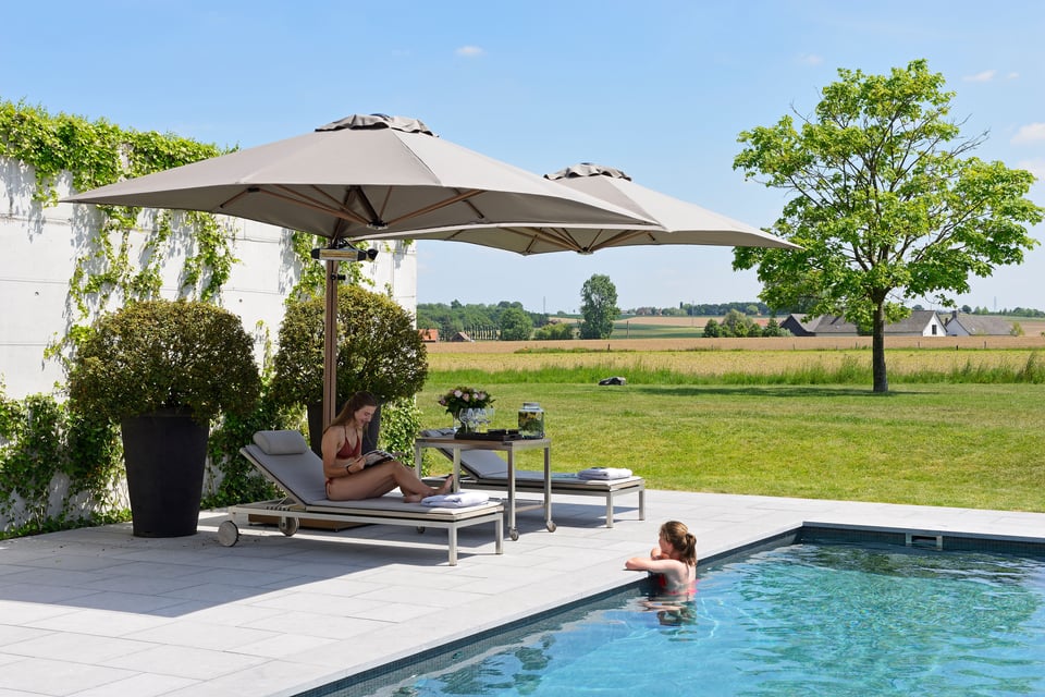 Prostor P6 in Sandweiß über zwei Sonnenliegen am Pool, Frau auf der Liege, offene Gartenlandschaft