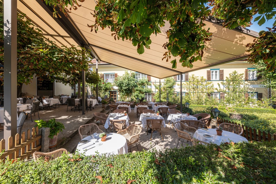 markilux pergola stretch überspannt einen bewachsenen Gastgarten mit gedeckten Tischen