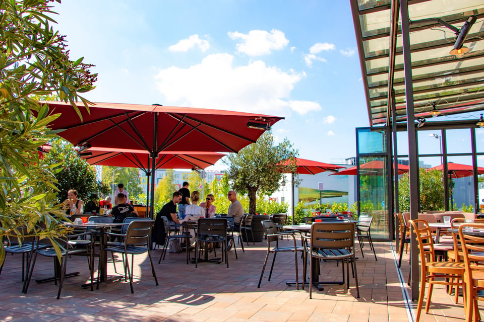 Roter MAY SCHATTELLO Gastroschirm über der Restaurant-Terrasse der L'Osteria Brunnthal, Gäste im Schatten