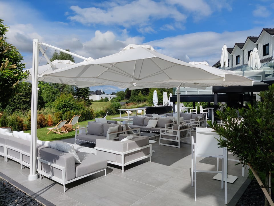Prostor P6 in Weiß über einer Lounge mit grauen Polstermöbeln auf einer Hotelterrasse